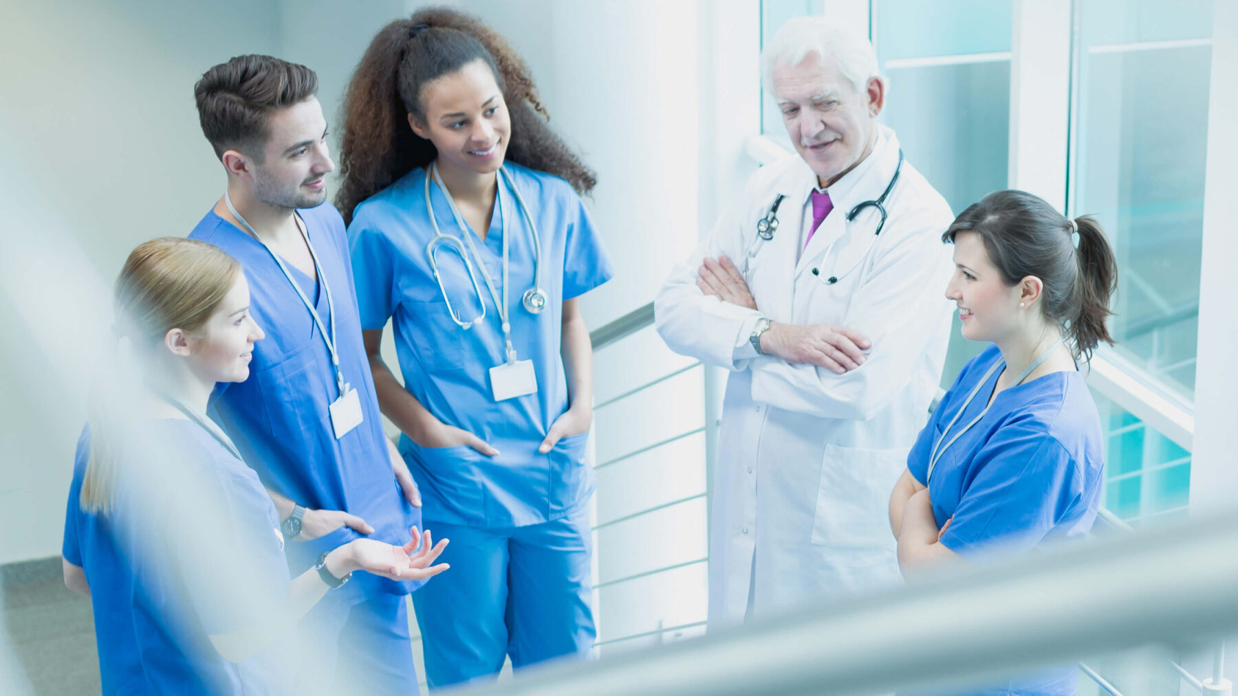 Arzt und Pflege im Gespräch auf dem Treppenabsatz im Krankenhaus